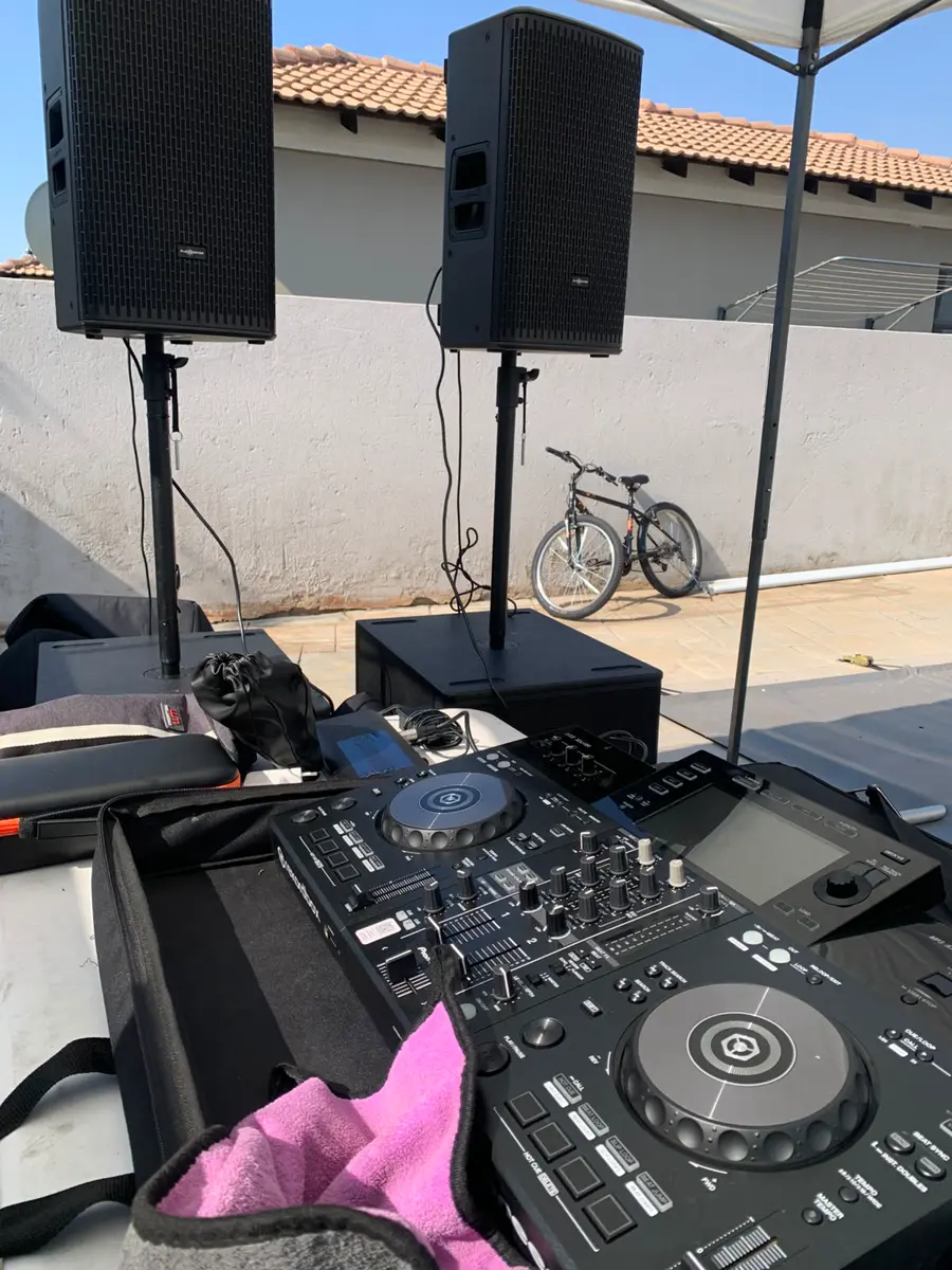 DJ controller and sound system set up outdoors under a canopy